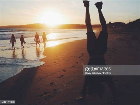 Group Of People Doing Handstands On Beach Photos And Premium High Res