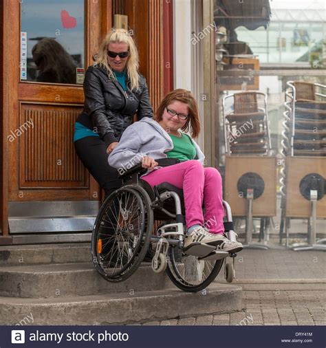 Caregiver Helping Disabled Girl In Wheelchair Up The Steps