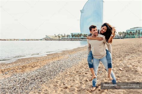 Boyfriend Giving Piggyback Ride To Girlfriend Against Sky At Beach