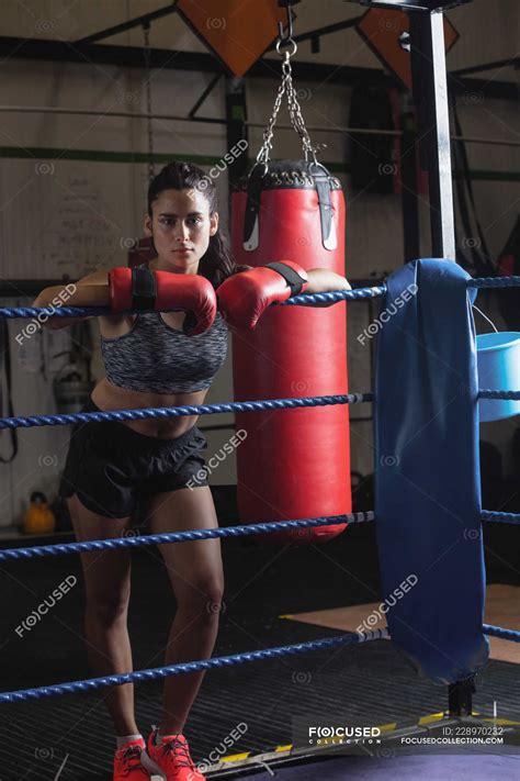 Portrait Of Female Boxer In Boxing Gloves Leaning On Boxing Ring Rope