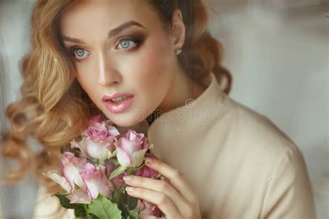 Portrait Of A Beautiful Delicate Sensual Blonde Girl With Roses Standing Outside The Window