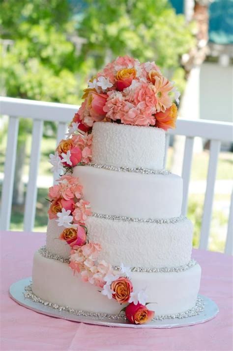 A Three Tiered Wedding Cake With Pink And Orange Flowers On The Top Is