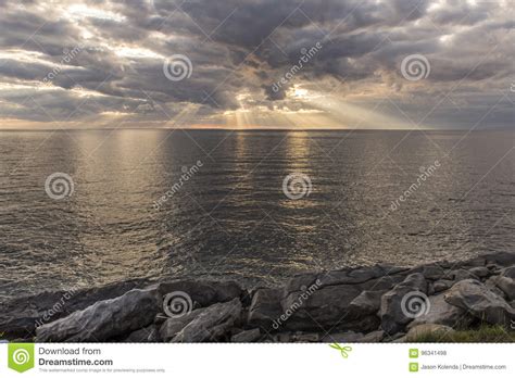 Sun Rays Shining Through Clouds Over The Ocean Stock Photo