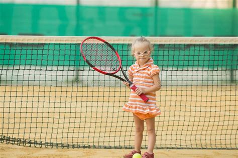 Красивая девушка при Синдром Дауна играя теннис Стоковое Фото изображение насчитывающей
