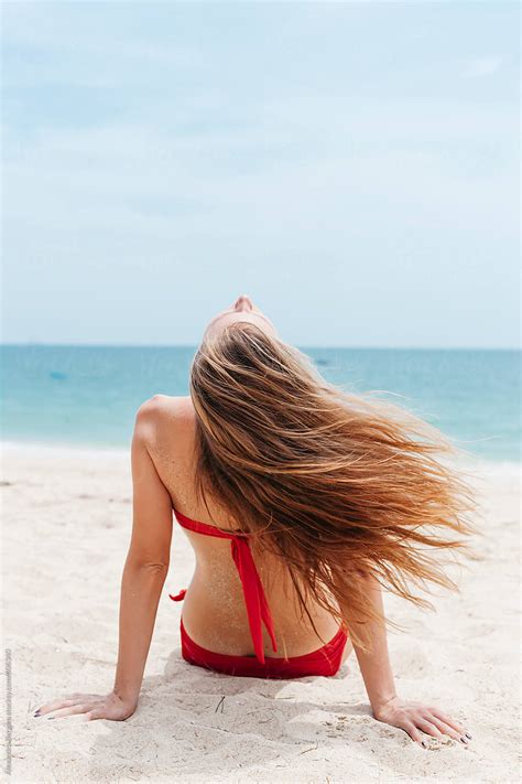 Woman Sit On Beach And The Wind Blows Her Hair By Stocksy Contributor