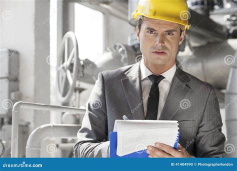 Portrait Of Confident Young Male Supervisor Writing On Clipboard In