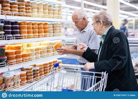 mature caucasian couple chooses pickled vegetables in the supermarket department stock image