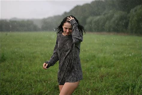 A Woman Walking Through A Field In The Rain