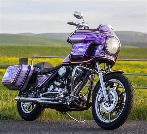 A Purple And Black Motorcycle Parked On The Side Of A Road Next To A Field