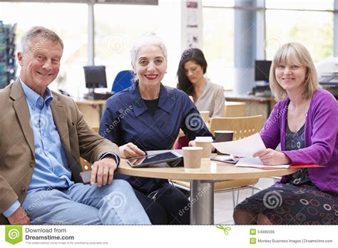 Three Mature Students Collaborating On Project Together Stock Photo