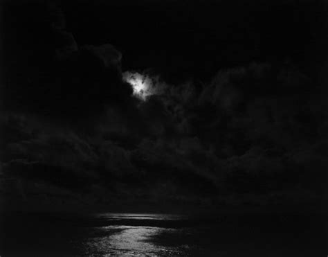 Black And White Photograph Of The Moon Over The Ocean With Dark Clouds