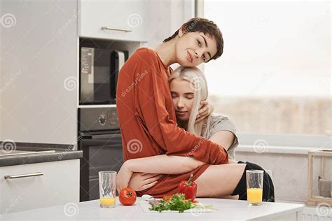 Het Sensuele En Tedere Jonge Lesbische Paar In Liefde Die In Keuken Knuffelen Terwijl Het Eten