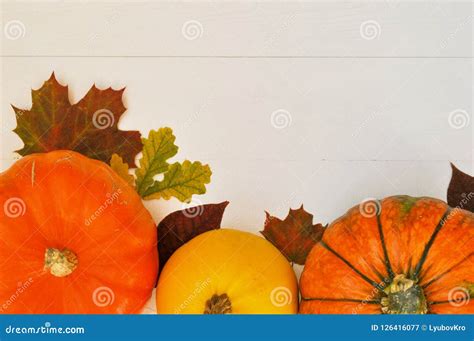 Yellow And Orange Pumpkins And Autumn Leaves On White Wooden Background