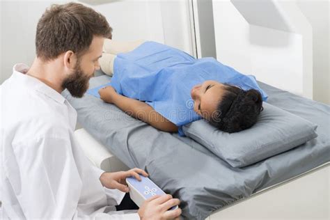 Doctor Examining Female Patient Lying On Bed In Hospital Stock Photo