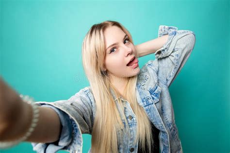 Positive Blond Haired Woman Taking Selfie On Blue Background Making Fun