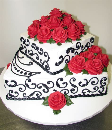 A Three Tiered Cake With Red Roses On The Top And Black Swirls Around It