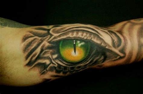 A Mans Arm With An Eye Tattoo On It Which Is Green And Orange