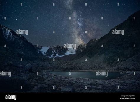 Milky Way And Night Starry Sky At The Mountain Lake With Snow Peaks