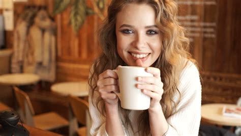 Happy Girl Drinking Coffee And Relaxing In Cafe Smiling And Looking At