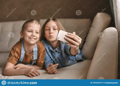 Beautiful Girls Take Selfies On Their Phone While Lying On The Sofa Sisters Take A Break From