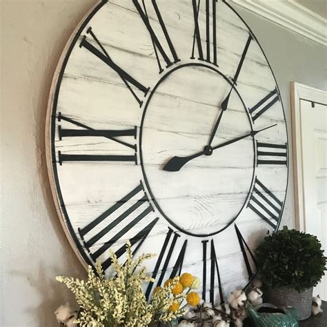 A Large Clock Mounted To The Side Of A Wall Next To A Potted Plant