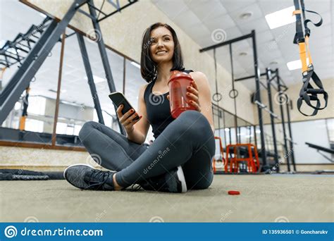 Young Healthy Woman With Bottle Water Resting In The Gym After Fitness