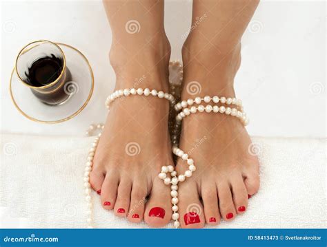 Closeup Photo Of Beautiful Female Feet With Red Pedicure On White And Decorated With Pearls