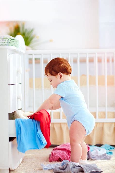Funny Infant Baby Throwing Out Clothes From The Dresser At Home Stock