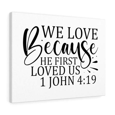 A White Canvas With The Words We Love Because He First Loved Us And