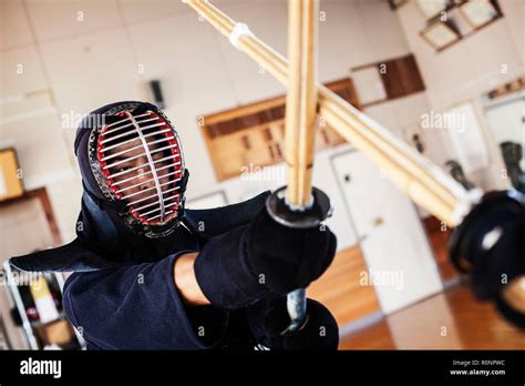 Two Japanese Kendo Fighters Wearing Kendo Masks Practicing With Wood