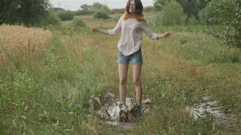 Beautiful Smiling Teen Girl Jumping In Very Muddy Puddle By