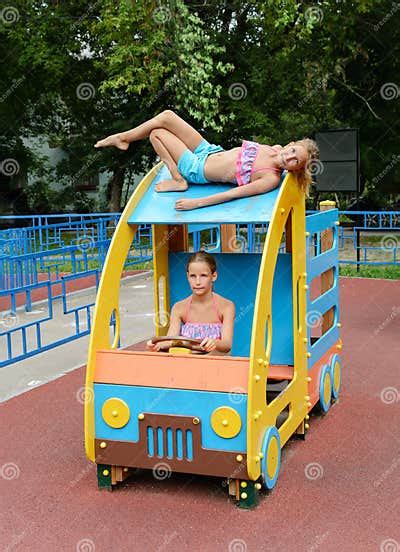 Tween Caucasian Girls Sits On Toy Wooden Car On Playground Stock Photo