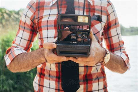 Close Up Of Retro Styled Man Holding Polaroid Camera In Front Of Chest