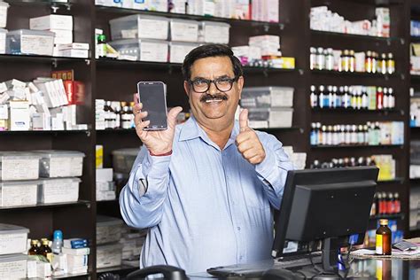 Indian Man Shopkeeper Showing Thumbsup With Cell Phone Chemist Shop