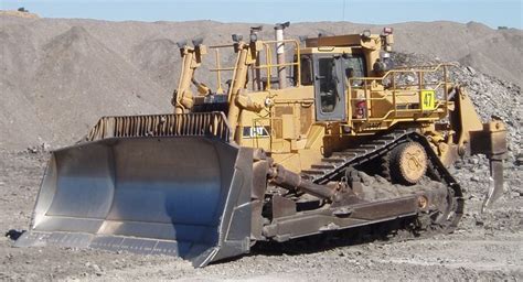 A Large Yellow Bulldozer Sitting On Top Of A Pile Of Dirt Next To A