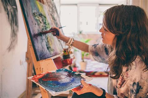 Woman Adds Details To Painting With Brush From Palette By Stocksy