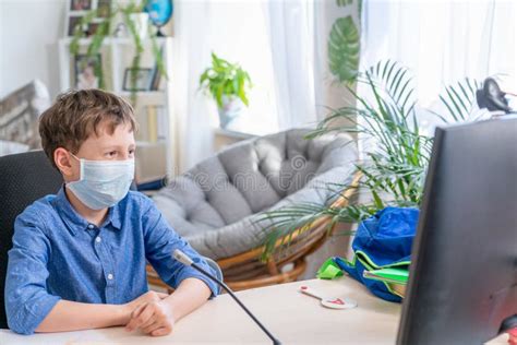 Boy In A Protective Mask Sitting At A Computer Watching A Training