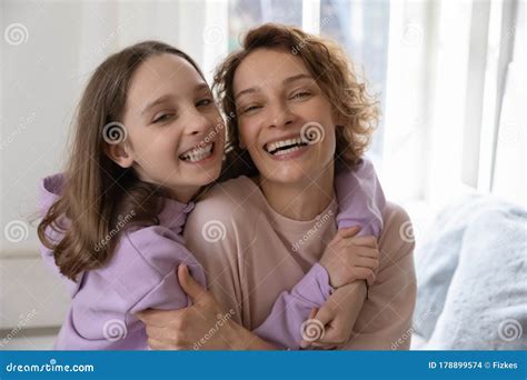 Cheerful Affectionate Teenage Daughter Hugging Young Mom Looking At