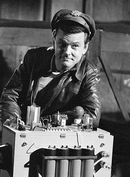 An Old Photo Of A Man In Leather Jacket And Cap Sitting Next To A Machine