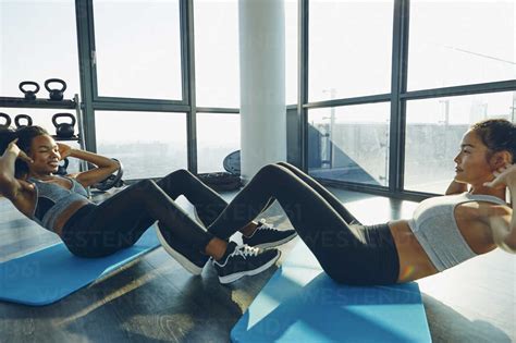 Two Young Women Exercising In Gym Doing Sit Ups Stock Photo