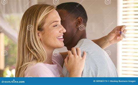 Hugging Multi Racial Couple In Bedroom At Home Celebrating Positive