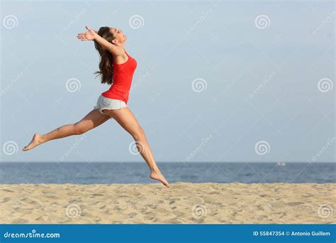 Tienermeisje In Het Rode Springen Gelukkig Op Het Strand Stock Foto