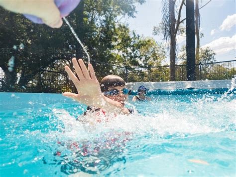 image of action shot of sibling squirting water fight in pool cooling off in summer austockphoto