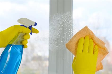 Female Hands In Yellow Rubber Gloves Wash The Windows With A Rag And