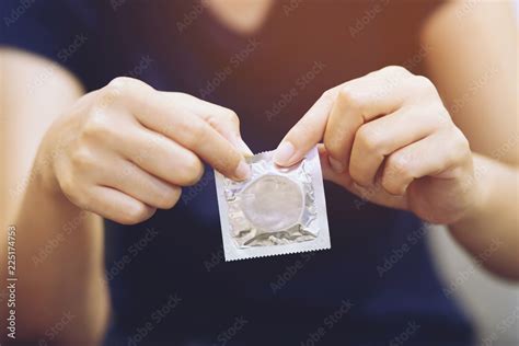condom ready to use in female hand give condom safe sex concept on the bed prevent infection