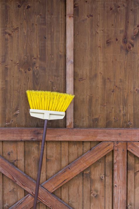 Broom Leaning At Wooden Wall Stock Photo