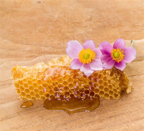 Honey Dripping Honey Comb With Flowers On Wooden Board Stock Image