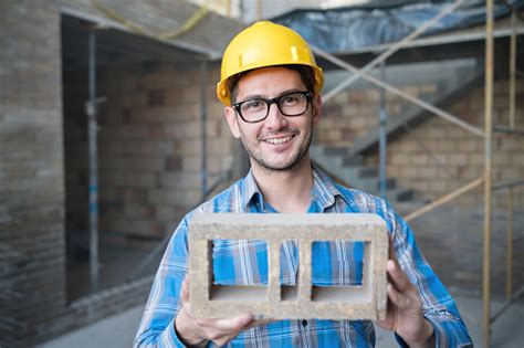 Portrait Of A Happy Construction Worker Holding A Brick Stock Photo