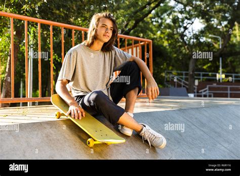 Photo Of Pleased Skater Boy 16 18 In Casual Wear Sitting On Ramp With