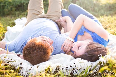 romantic and whimsical engagement photo of couple laying down in a hay field kate saler